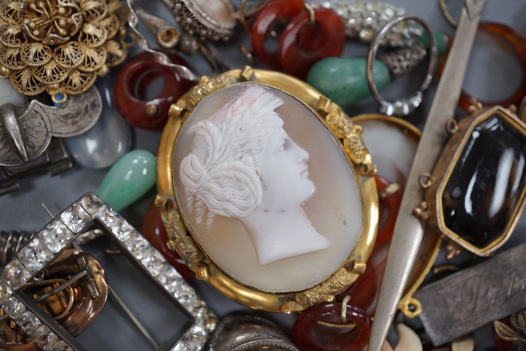 Assorted jewellery including jade pendant, yellow metal buckle brooch, modern silver hinged bangle, cameos, unmounted oval moonstone, agate set white metal buckle brooch, 800 standard paper knife etc.